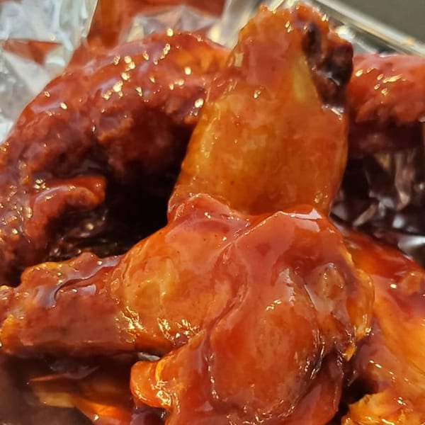 Close-up of several chicken wings coated in a glistening, reddish-brown sauce.